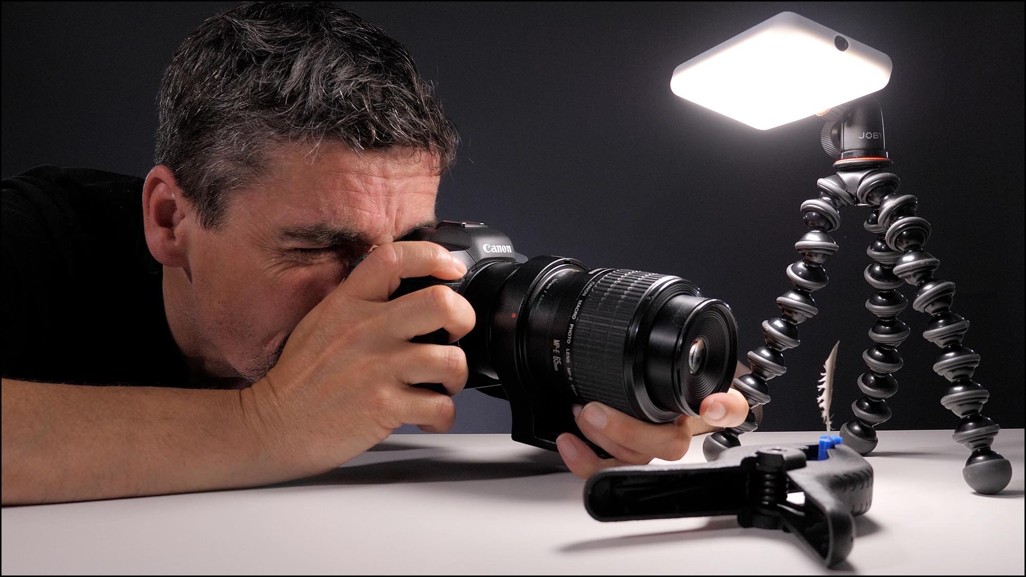 man with camera taking macro picture of feather