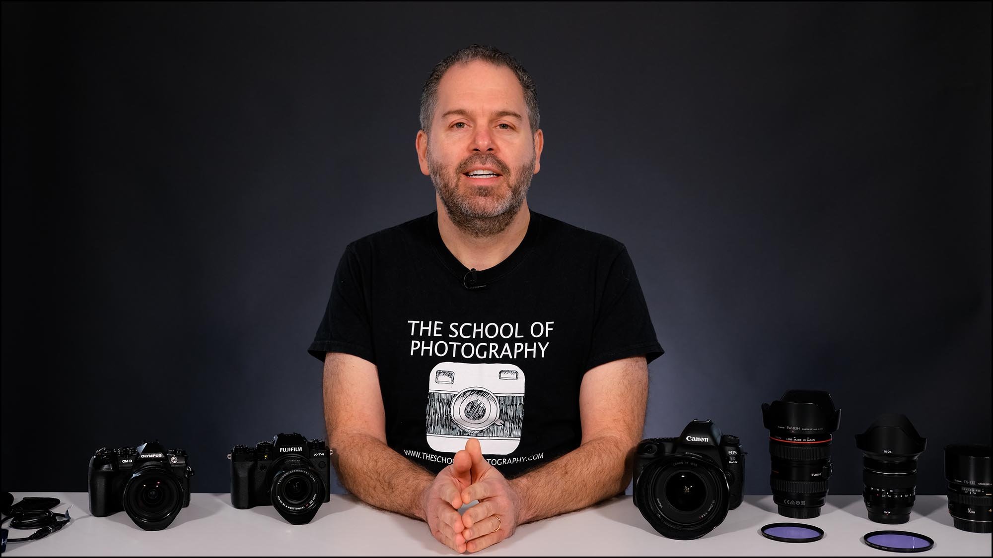 Man presenting at desk that has cameras on it