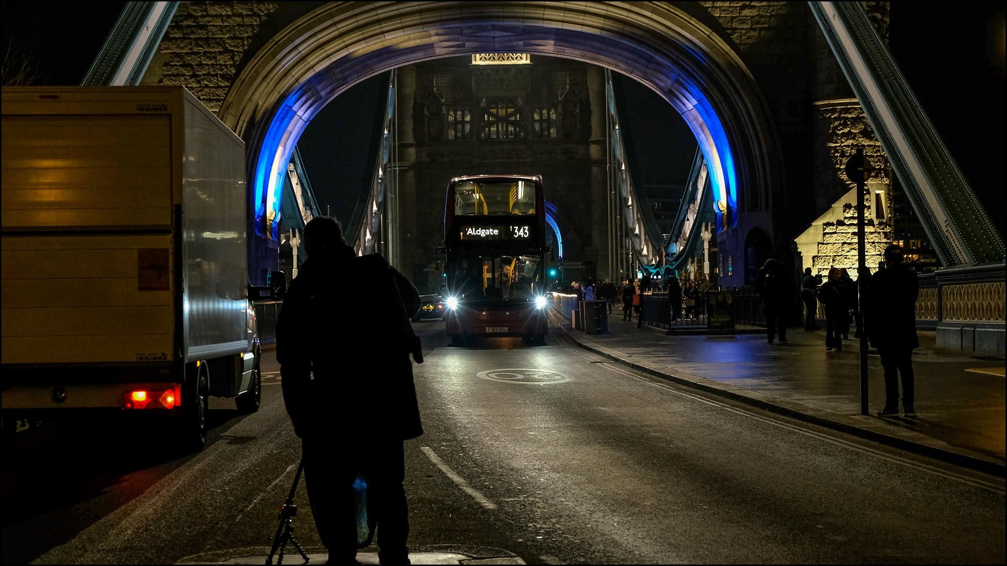 Man on Tower Bridge taking pictures of passing cars