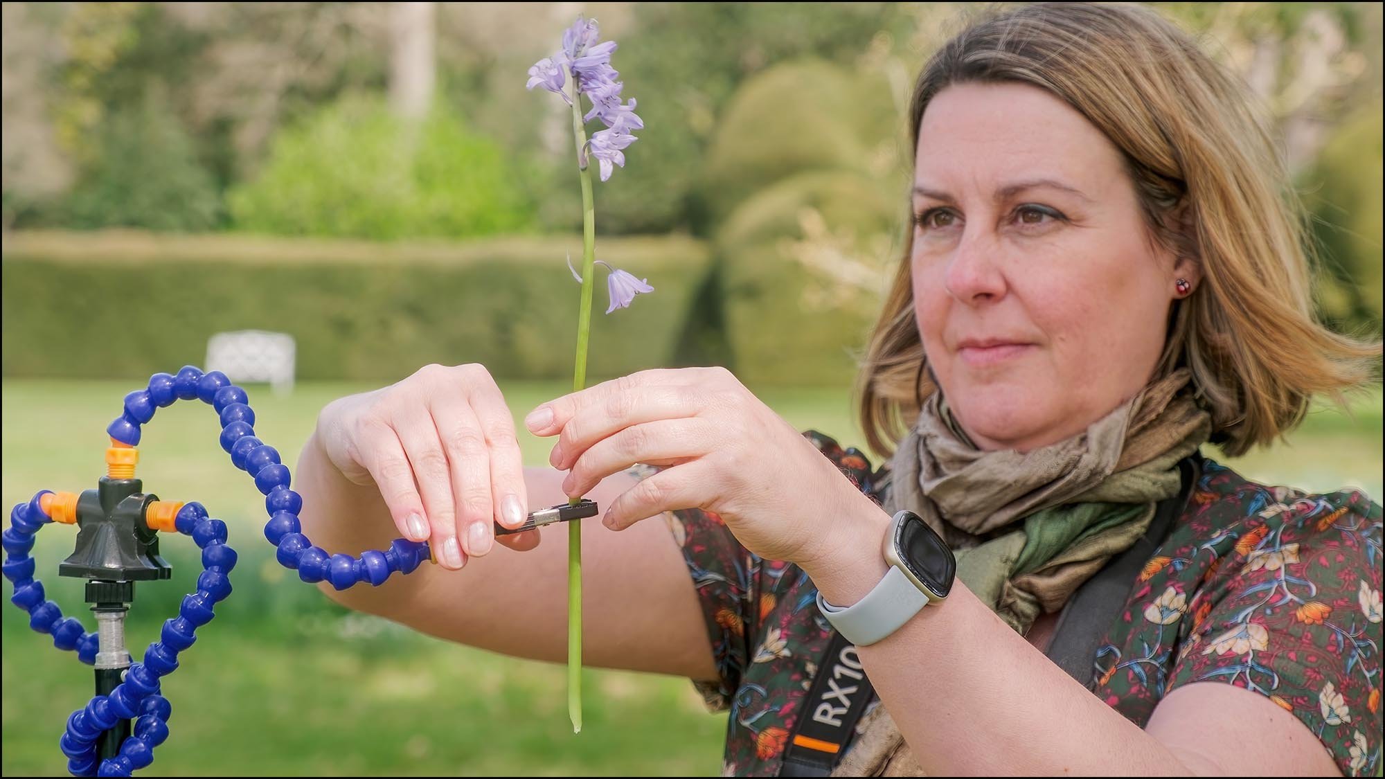 Photography instructor demonstrating how to position a bluebell on a clamp for flower photography setup