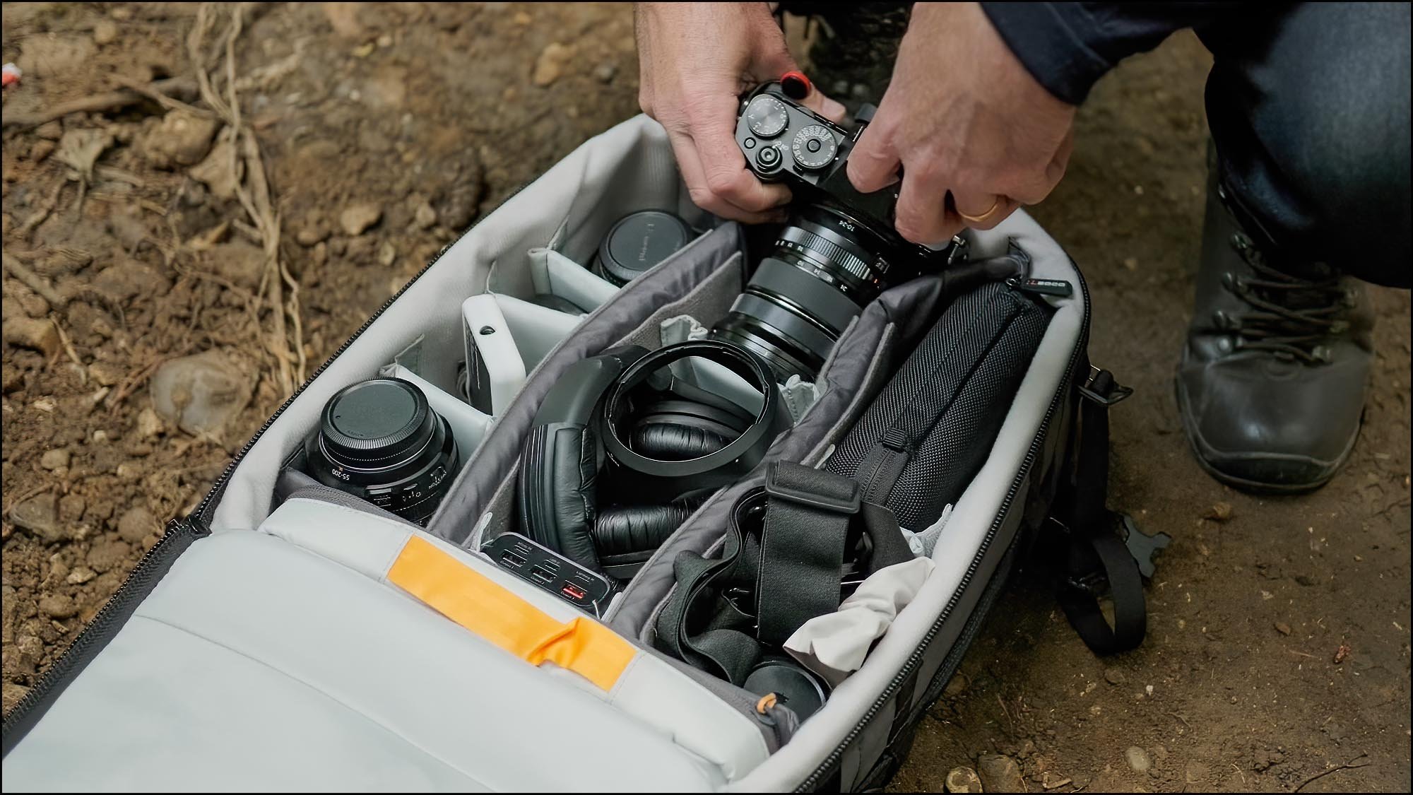 Photographer organising camera gear and lenses in a backpack during a photography course equipment lesson
